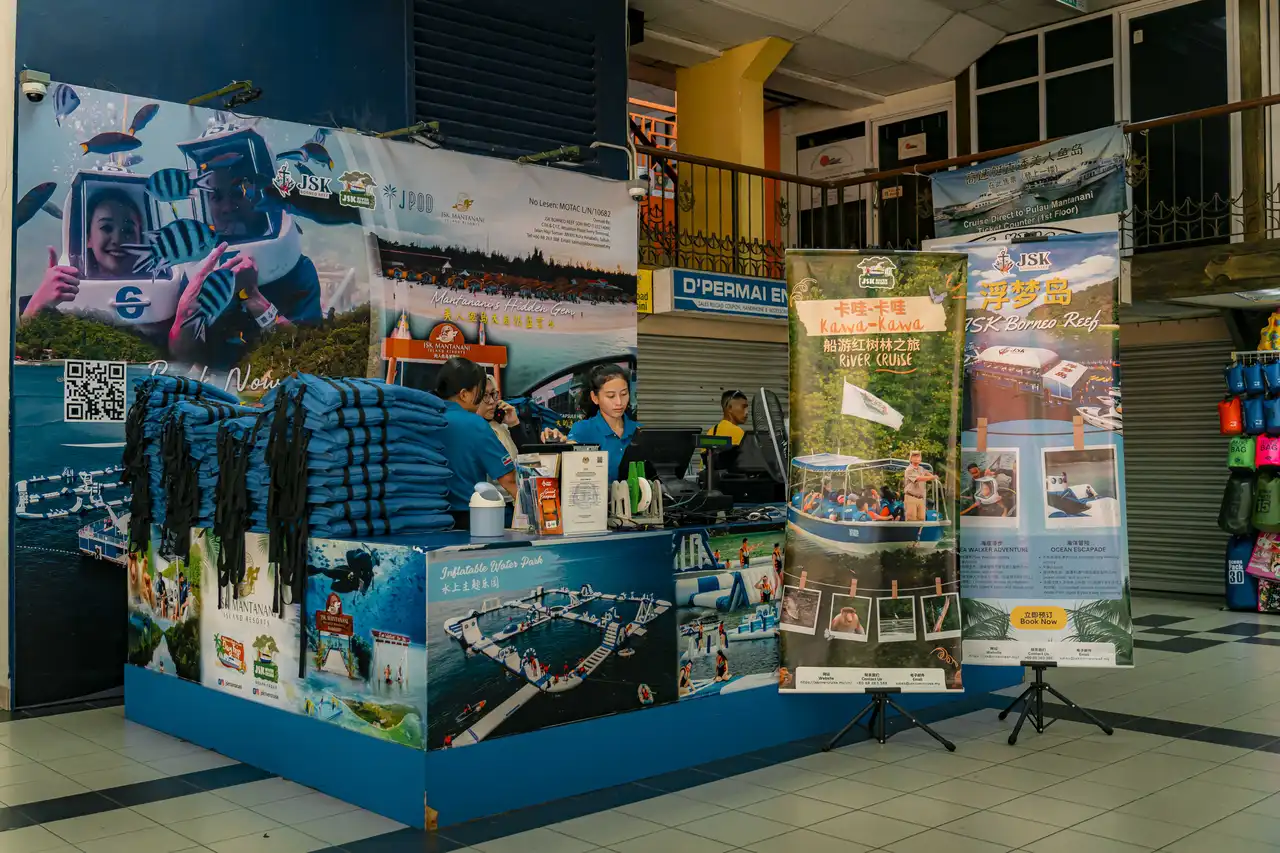Tourism booth promoting river cruises and island resorts with staff and promotional materials.