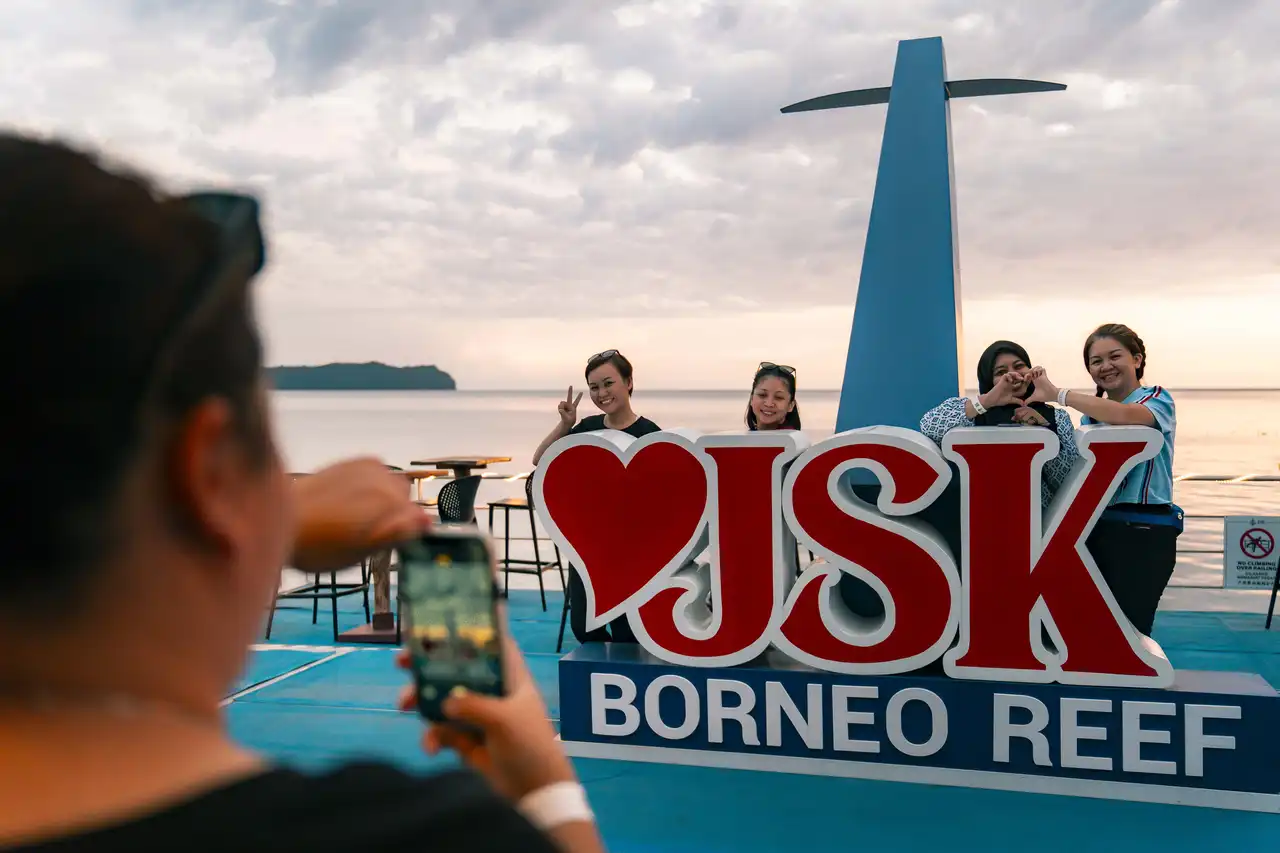 Group of women posing for a photo at JSK Floating Island with a scenic ocean backdrop.
