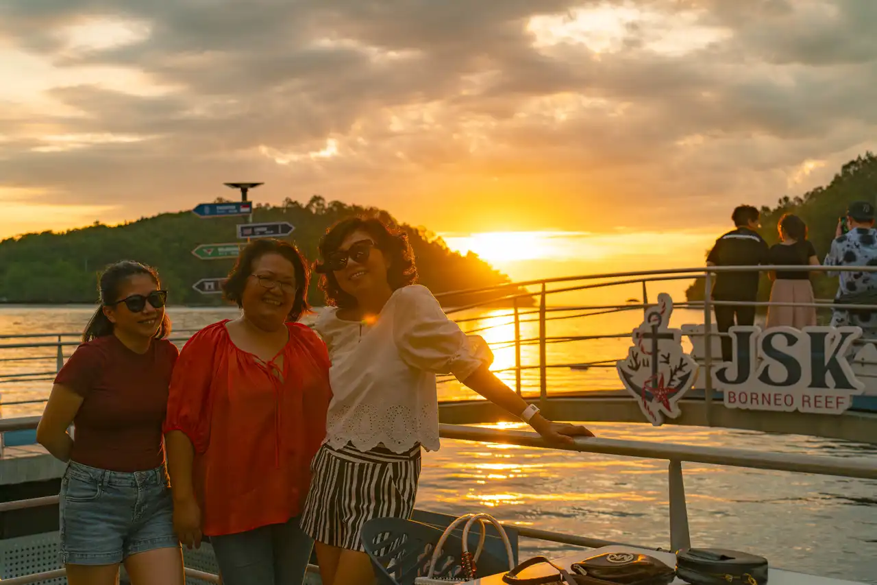 Three women smiling during a sunset at JSK Floating Island.